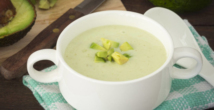 Refreshing avocado soup with yogurt, garnished with fresh herbs and a drizzle of olive oil