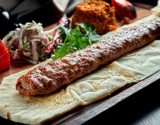 Delicious Adana Kebab recipe with grilled minced lamb, aromatic spices, and served with fresh vegetables