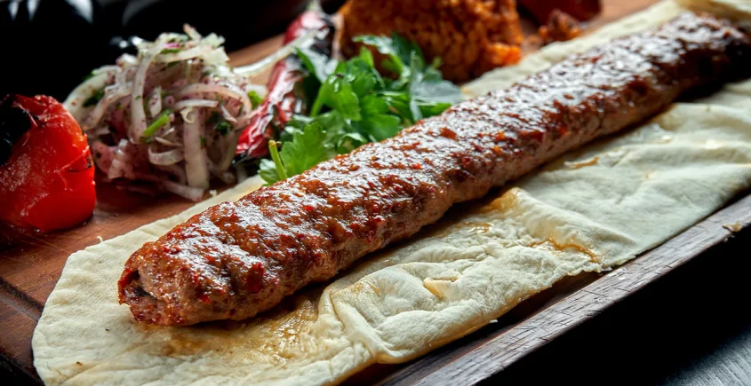 Delicious Adana Kebab recipe with grilled minced lamb, aromatic spices, and served with fresh vegetables